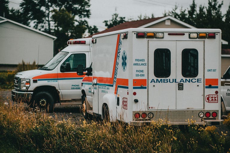 White and Red Ambulance Truck on Green Grass Field