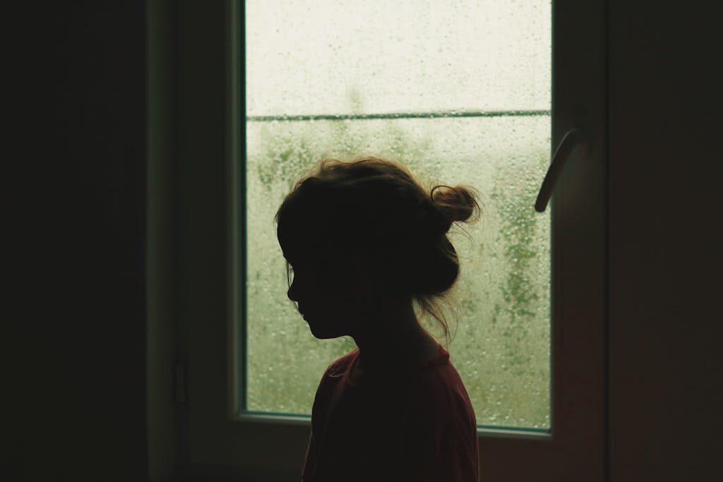 Girl Standing near Window with Raindrops