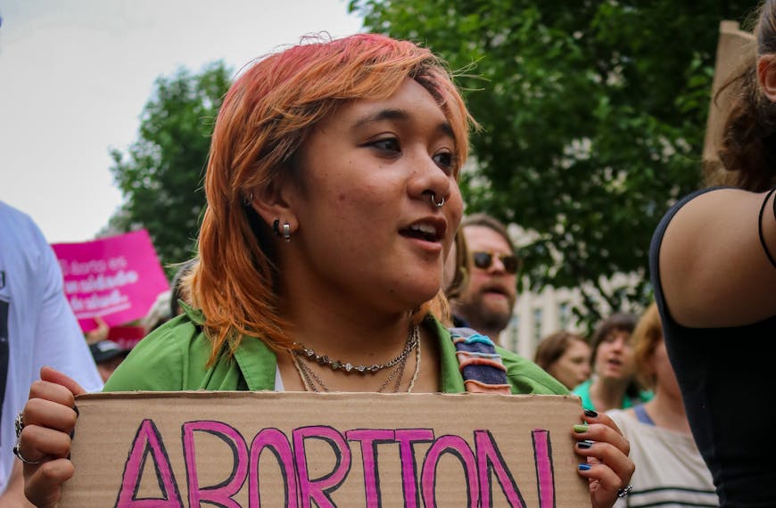 Woman Holding a Banner and Walking in a Protest about Abortion Rights