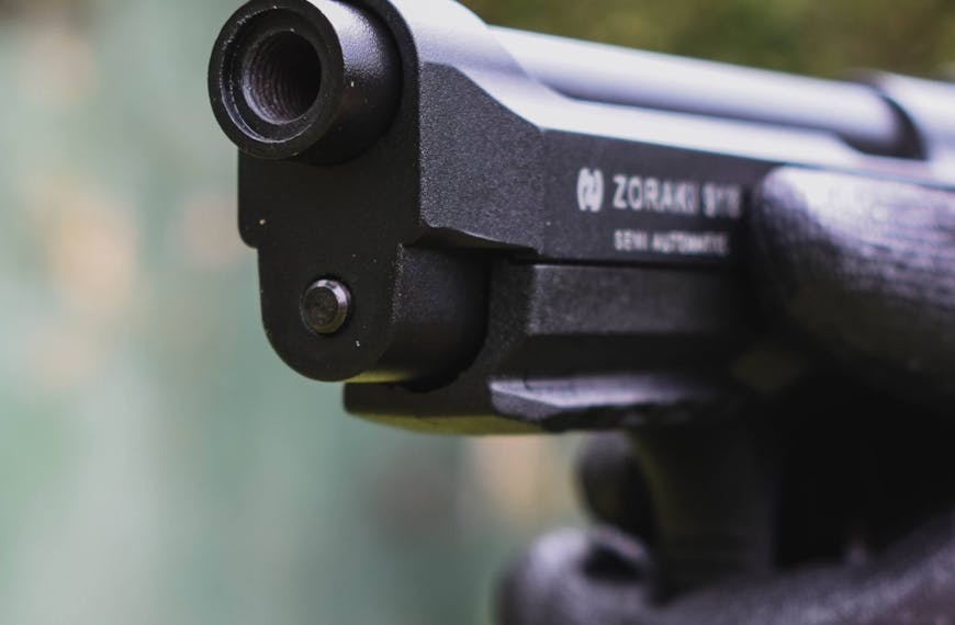 Close-up Photo of Gloved Hands Aiming a Gun