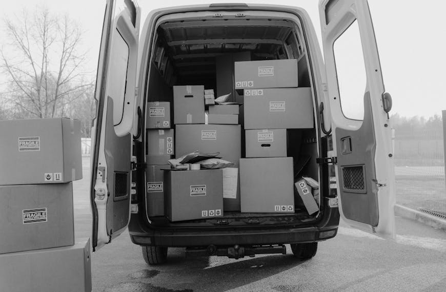 Open delivery van loaded with various boxes labeled as fragile, ready for shipment.
