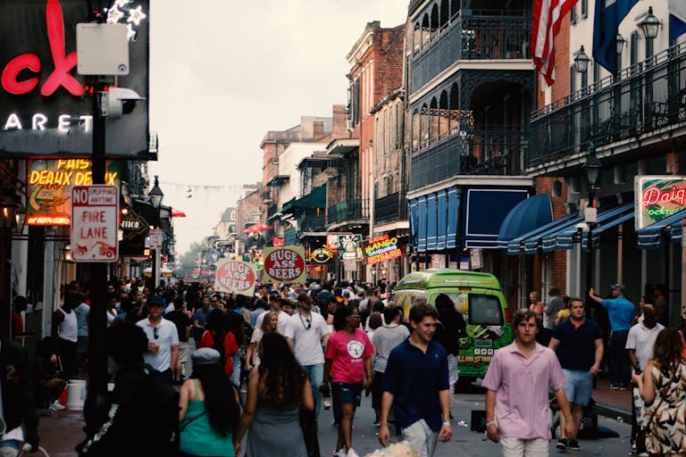 Bustling street scene in the New Orleans French Quarter filled with tourists and local shops.