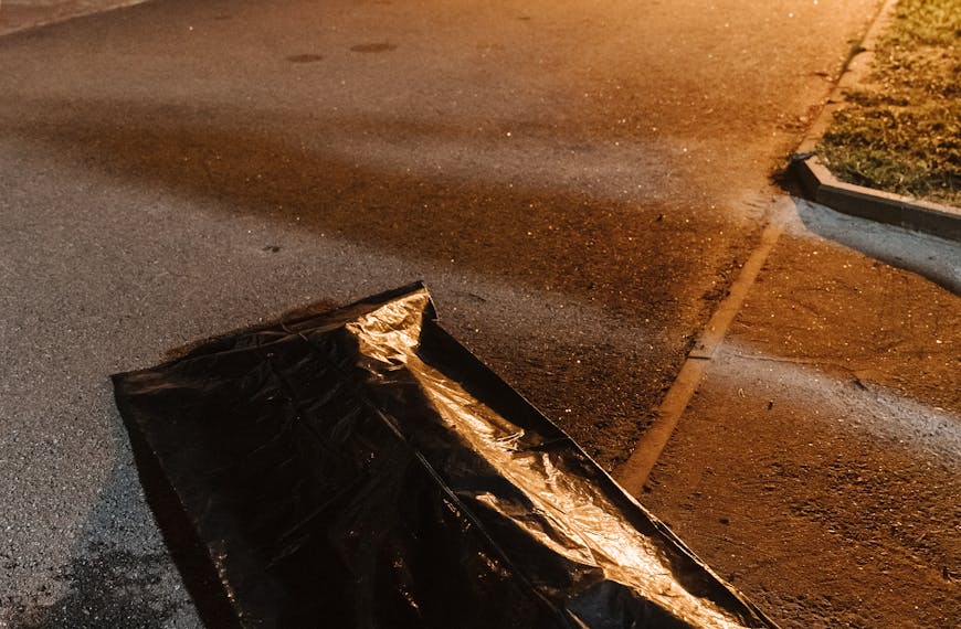 Urban crime scene with police tape and evidence bag under streetlights at night.