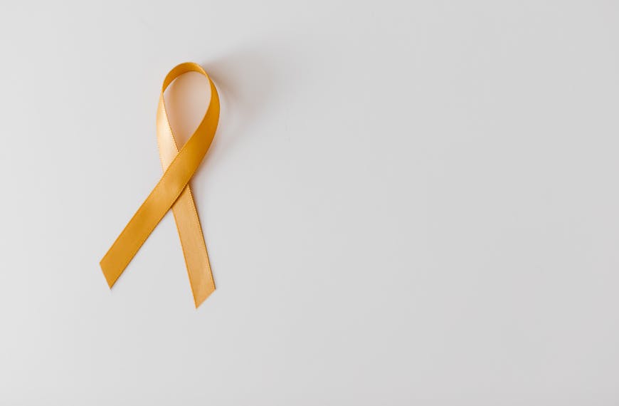 Golden ribbon symbolizing awareness on a white background, perfect for campaigns.