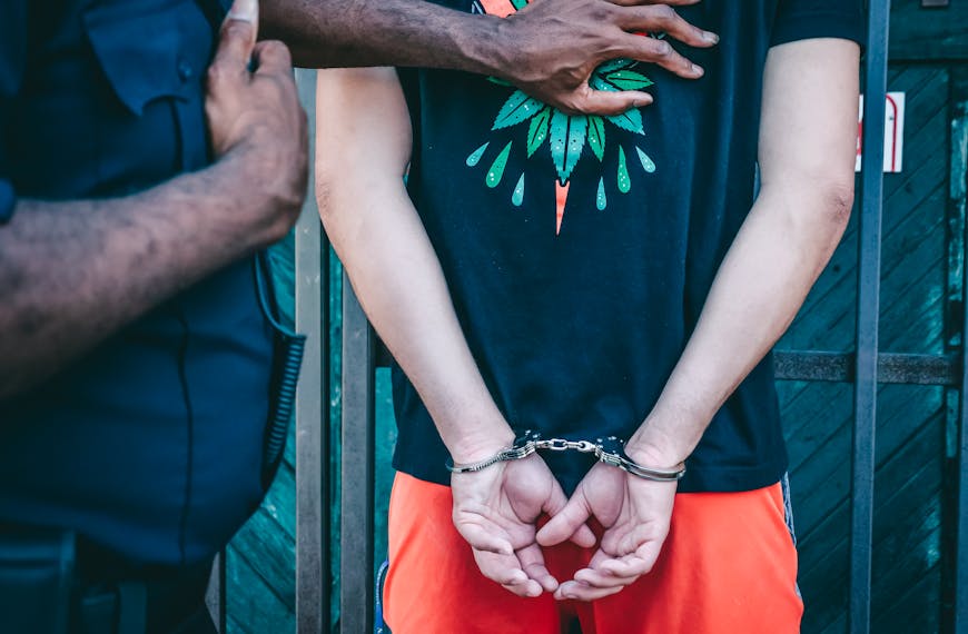 Close-up of a handcuffed person under arrest by a police officer outdoors.