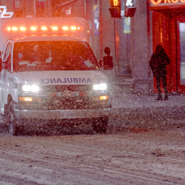Ambulance on a snowy street during a winter emergency response at night.