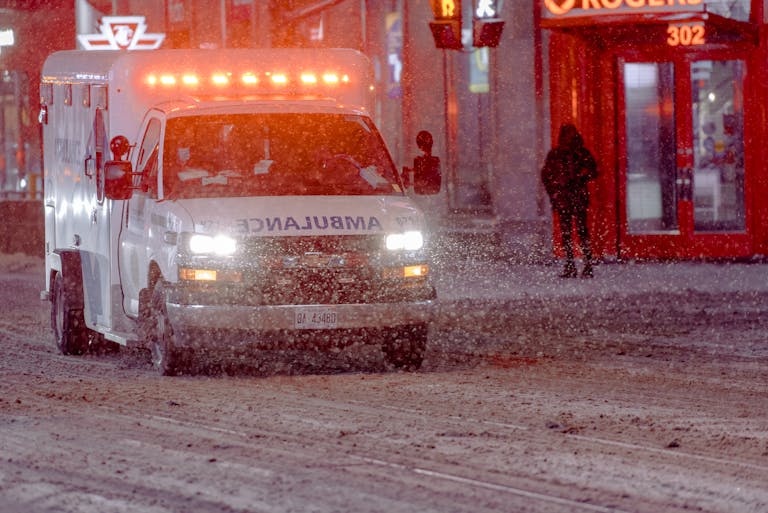 Ambulance on a snowy street during a winter emergency response at night.