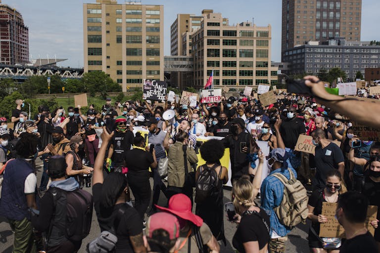 A large and diverse crowd gathers for a peaceful protest advocating for racial justice and equality in an urban setting.
