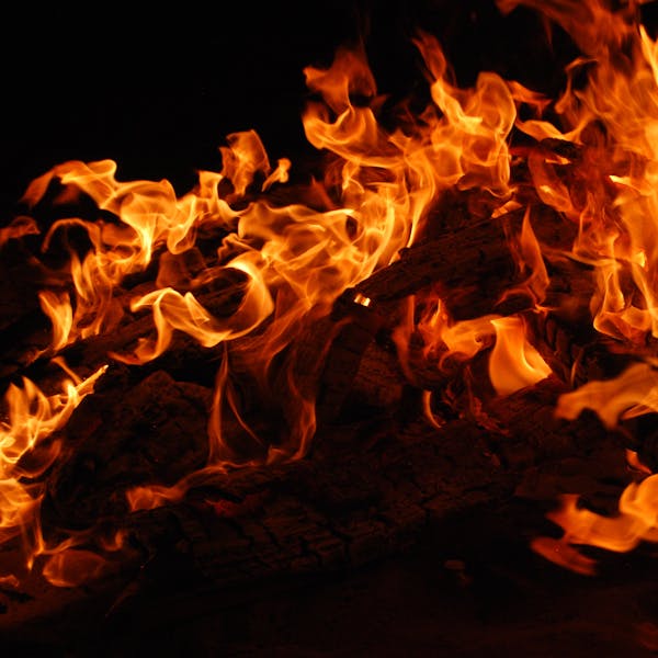 Close-up of a blazing bonfire with intense flames against a dark background.
