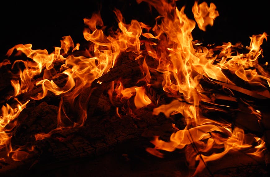 Close-up of a blazing bonfire with intense flames against a dark background.